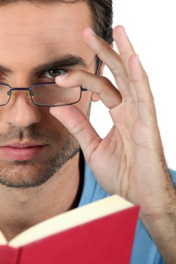 Closeup of a man in glasses reading a book clipart