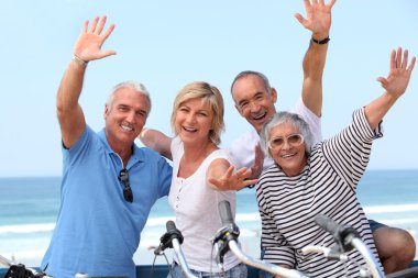 Middle-aged couple on bike ride by the sea clipart