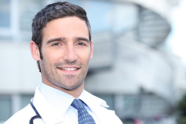 Doctor standing outside the hospital building clipart