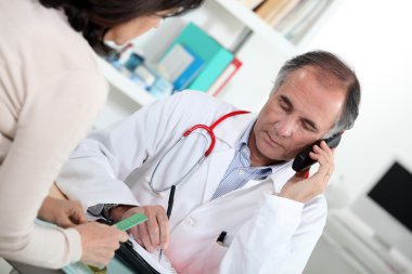 Doctor talking on the phone during a consultation clipart