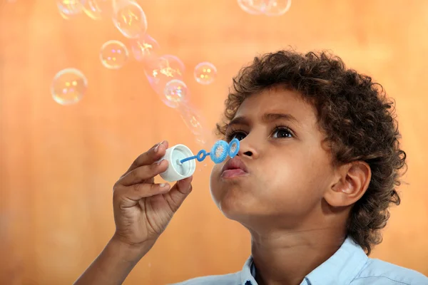Schattige gemengd ras kleine jongen zeepbellen blazen — Stockfoto