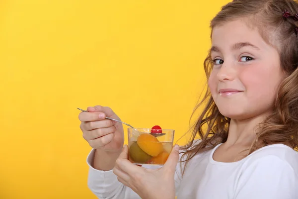 Liten flicka äter en fruktsallad — Stockfoto