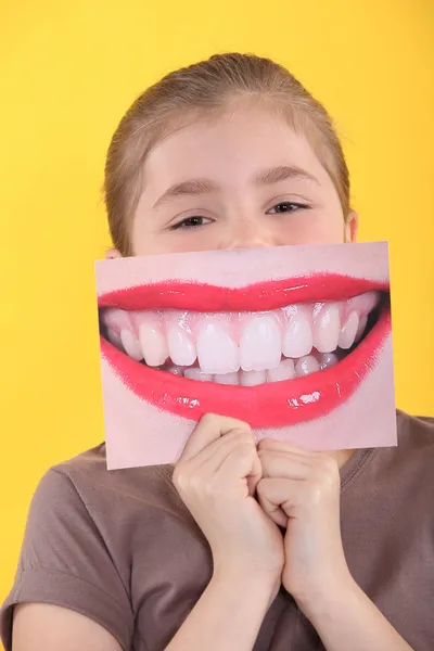 Κοπέλα που κρατά μια διευρυμένη εικόνα για τα δόντια της μπροστά από το στόμα — Φωτογραφία Αρχείου