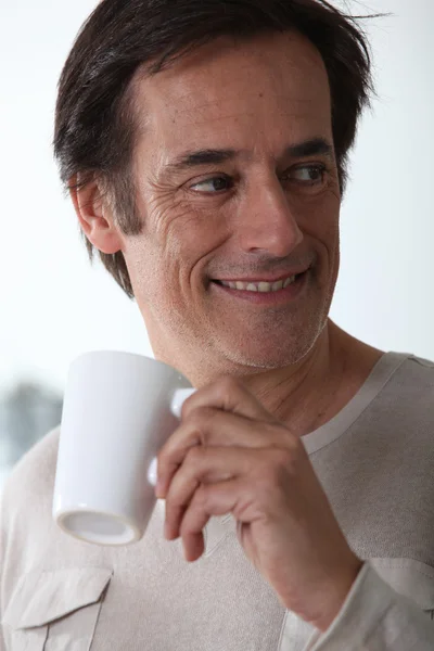 Человек улыбается с чашкой чая . — стоковое фото