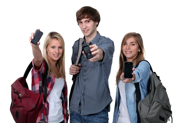 Tres estudiantes adolescentes con mochilas y teléfonos celulares —  Fotos de Stock
