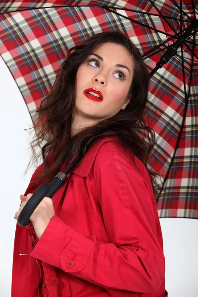 Γυναίκα σε ένα κόκκινο παλτό με μια ομπρέλα ταρτάν — Φωτογραφία Αρχείου