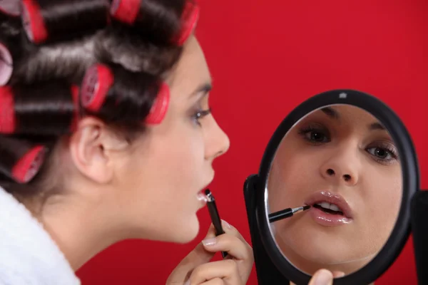 Mujer usando rodillos para el cabello aplicando maquillaje — Foto de Stock