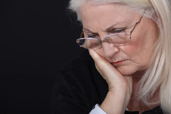 Grandmother looking concerned against black background — Stock Photo, Image
