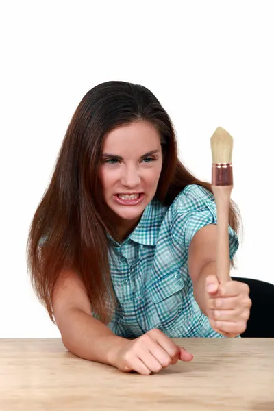 Braunhaarige Frau entblößt ihre Zähne und hält einen Pinsel in der Hand — Stockfoto