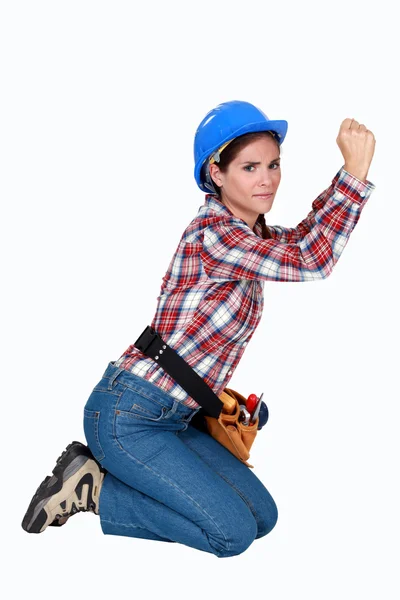 Vrouwelijke bouwvakker geknield op witte achtergrond — Stockfoto
