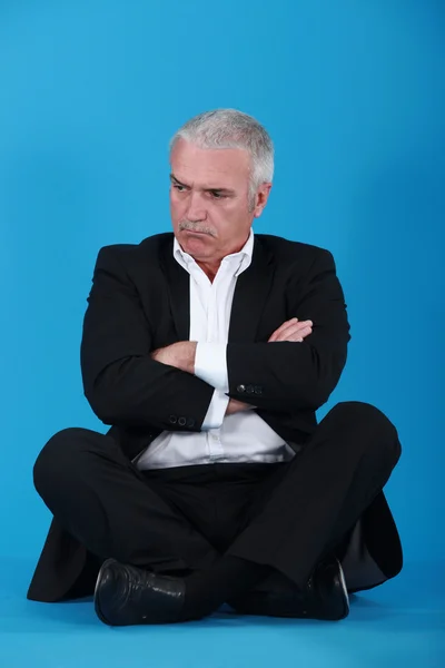 Wütender Senior-Geschäftsmann sitzt im Schneidersitz — Stockfoto