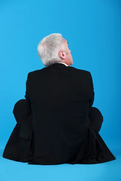 Vista posteriore dell'uomo d'affari anziano seduto sul pavimento — Foto Stock