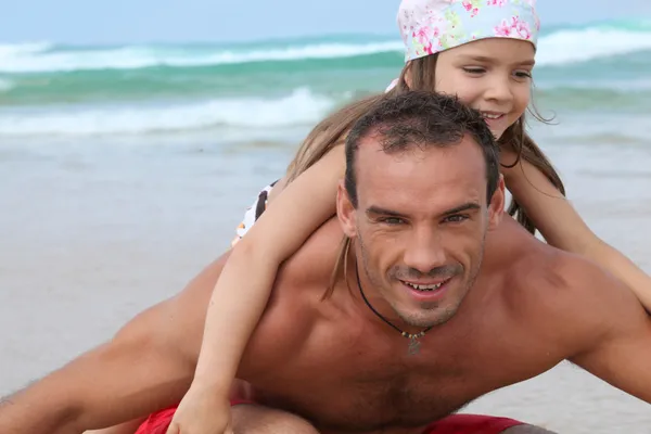 Маленькая девочка и ее отец играют на пляже — стоковое фото