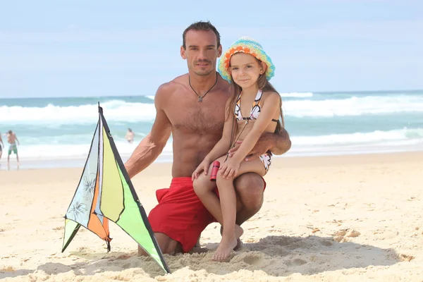 Człowiek i dziewczynka gra z latawcem na plaży — Zdjęcie stockowe