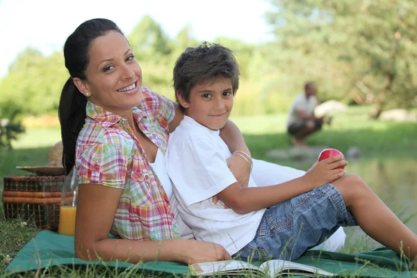 En mamma och hennes son på picknick, fadern är fiske — Stockfoto