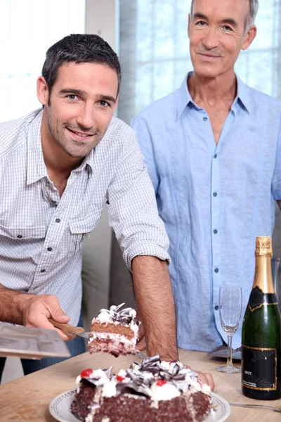 Двое мужчин режут торт — стоковое фото