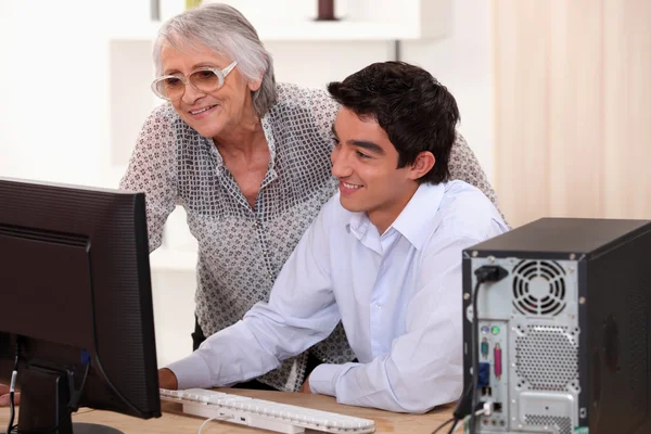 Jonge man zijn oma helpen met haar computer. — Stockfoto