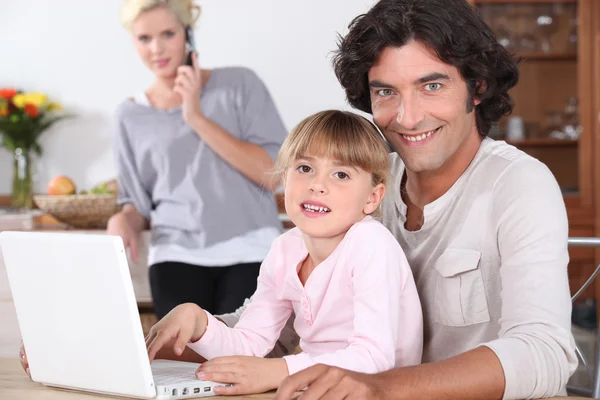 Föräldrar och liten flicka med laptop — Stockfoto