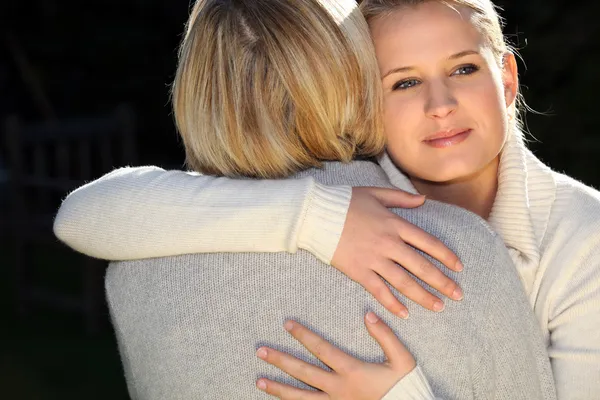 Een vrouw en haar dochter knuffelen. — Stockfoto