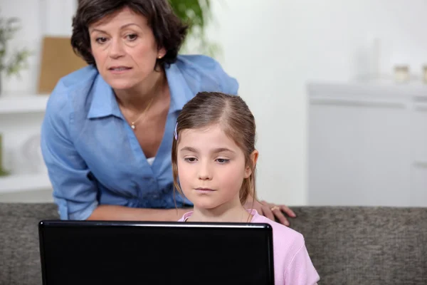 Mulher e menina olhando para um computador portátil — Fotografia de Stock