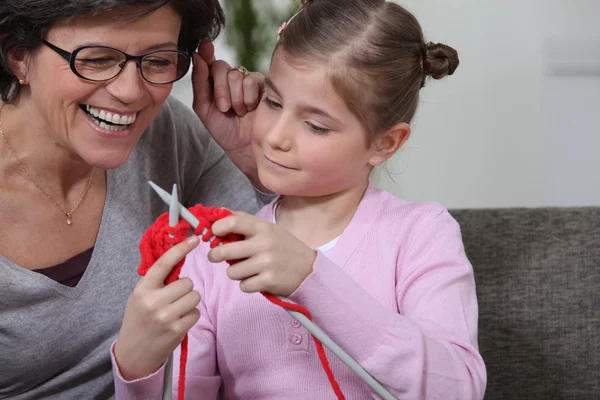 Een moeder die haar dochter onderwijzen hoe te breien. — Stockfoto
