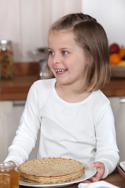 Klein meisje houdt van een plaat van pannenkoeken — Stockfoto