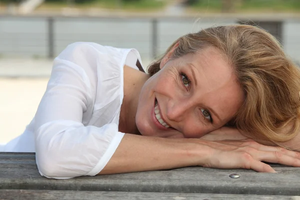 Närbild av en leende kvinna som sitter utomhus — Stockfoto