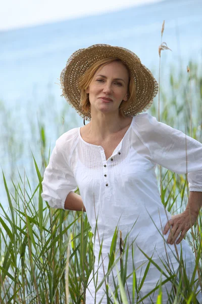Женщина в окружении тростника у озера — стоковое фото