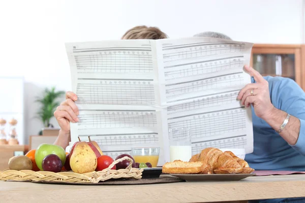 Jornal de leitura de casal durante o café da manhã — Fotografia de Stock