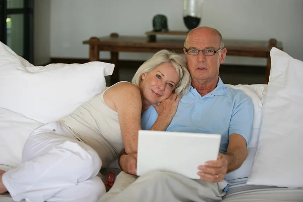 Äldre par på en soffa med bärbar dator — Stockfoto
