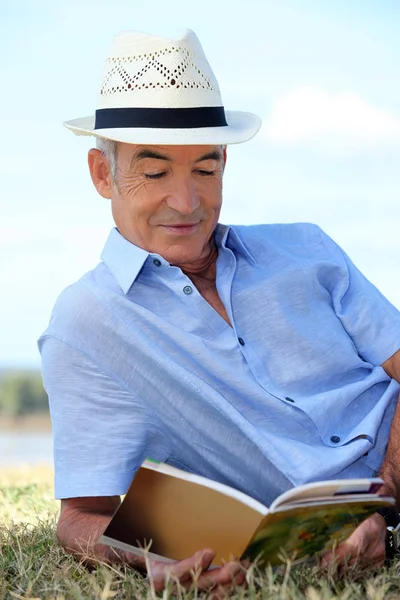 Senior reading a book in the park — Stock Photo, Image