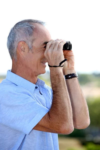Uomo anziano guardando attraverso binocoli — Foto Stock