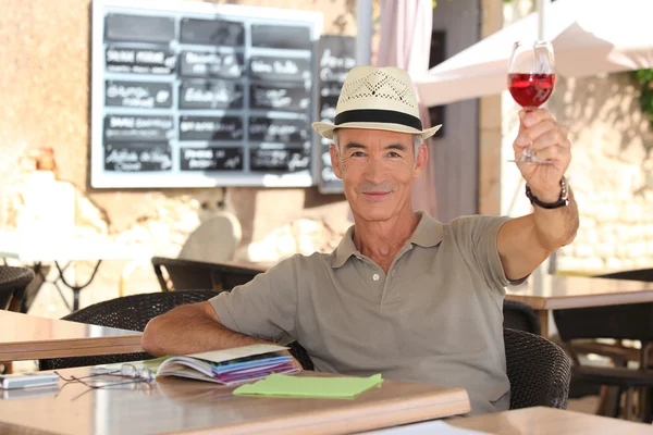 Senior man toasting on a cafe terrace — Stock Photo, Image