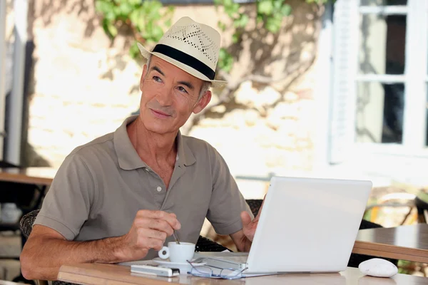 Пенсионер с ноутбуком за пределами кафе — стоковое фото