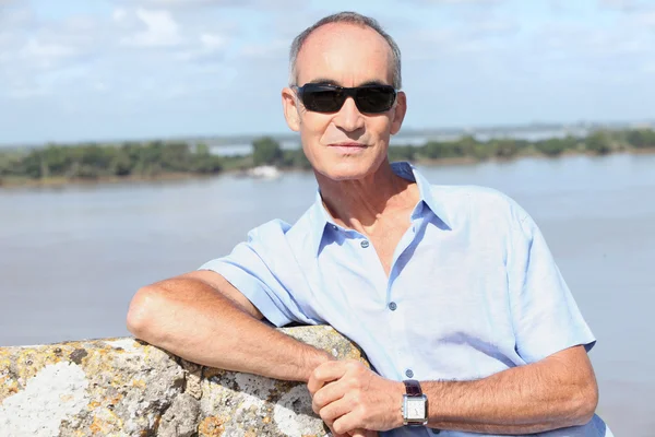 Un hombre de 65 años frente a un río y una isla — Foto de Stock