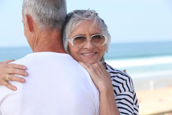 Älteres Paar, das sich am Strand umarmt — Stockfoto
