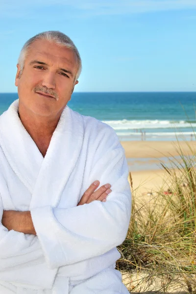 Middle aged man in a toweling robe by the sea — Stock Photo, Image