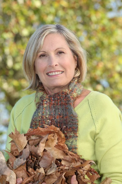 Žena s náručí podzimní listí — Stock fotografie