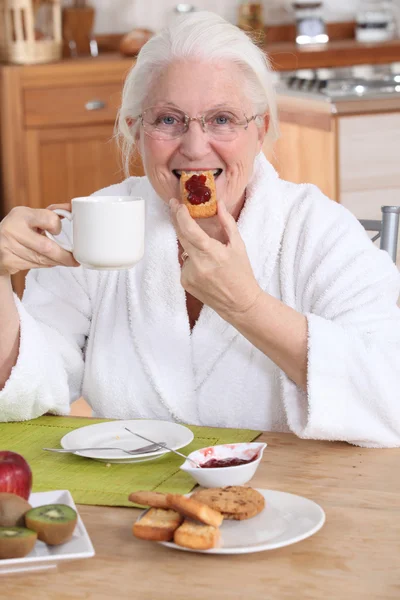 Oude dame ontbijten in de keuken — Stockfoto