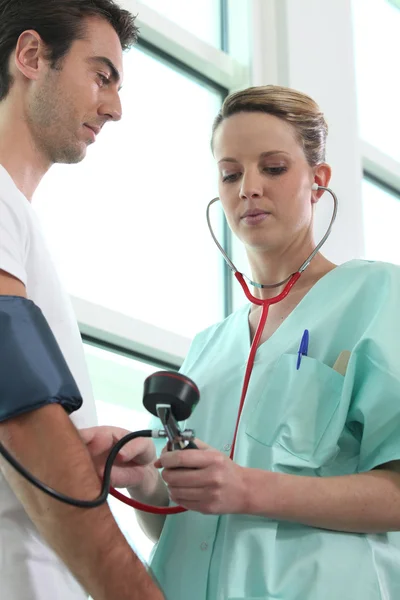 Enfermera revisando la presión arterial de un paciente — Foto de Stock