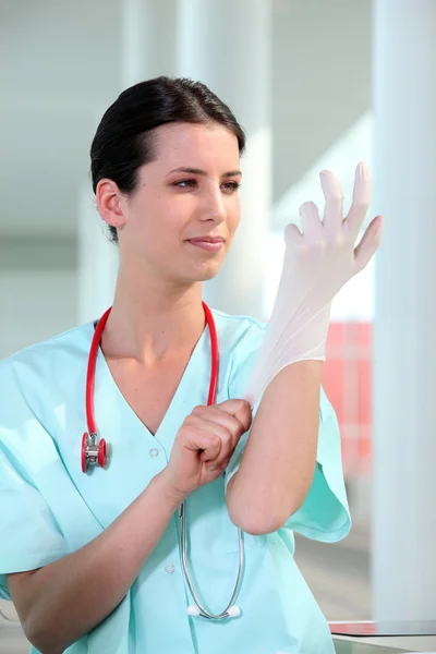 Female doctor putting on rubber glove — Stock Photo, Image