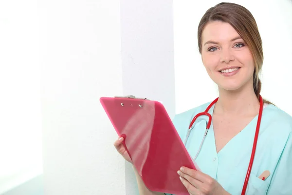 Enfermeira olhando prancheta sorrindo — Fotografia de Stock