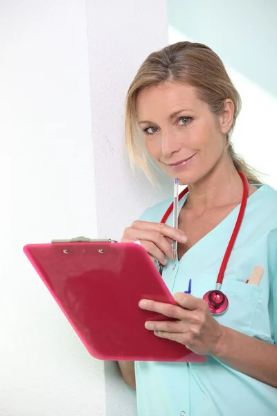 A cute nurse with a pink clipboard. — Stock Photo, Image