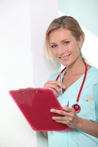 A female doctor taking notes and smiling at us. — Stock Photo, Image