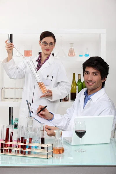 男人和女人在实验室测试酒 — 图库照片