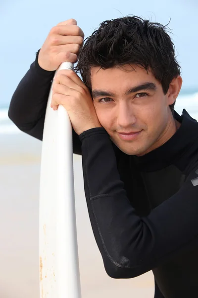 Jonge man in natte suite stond met surfboard — Stockfoto