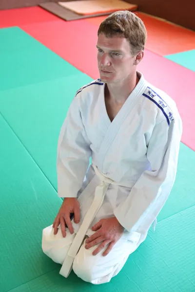 Dizlerinin üzerinde erkek judo mat — Stok fotoğraf