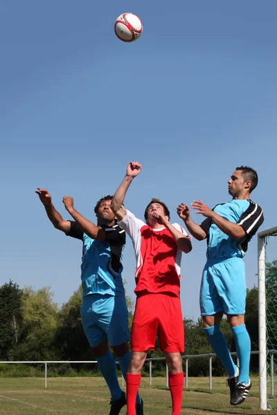 Футболисты прыгают за мячом — стоковое фото