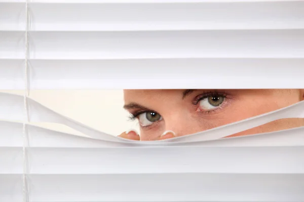 Woman peering through blinds — Stock Photo, Image