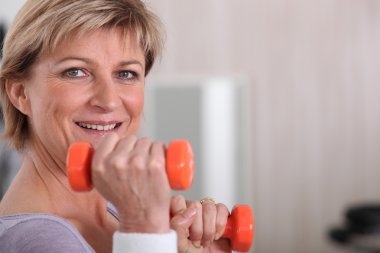 Mature woman using dumbbells clipart